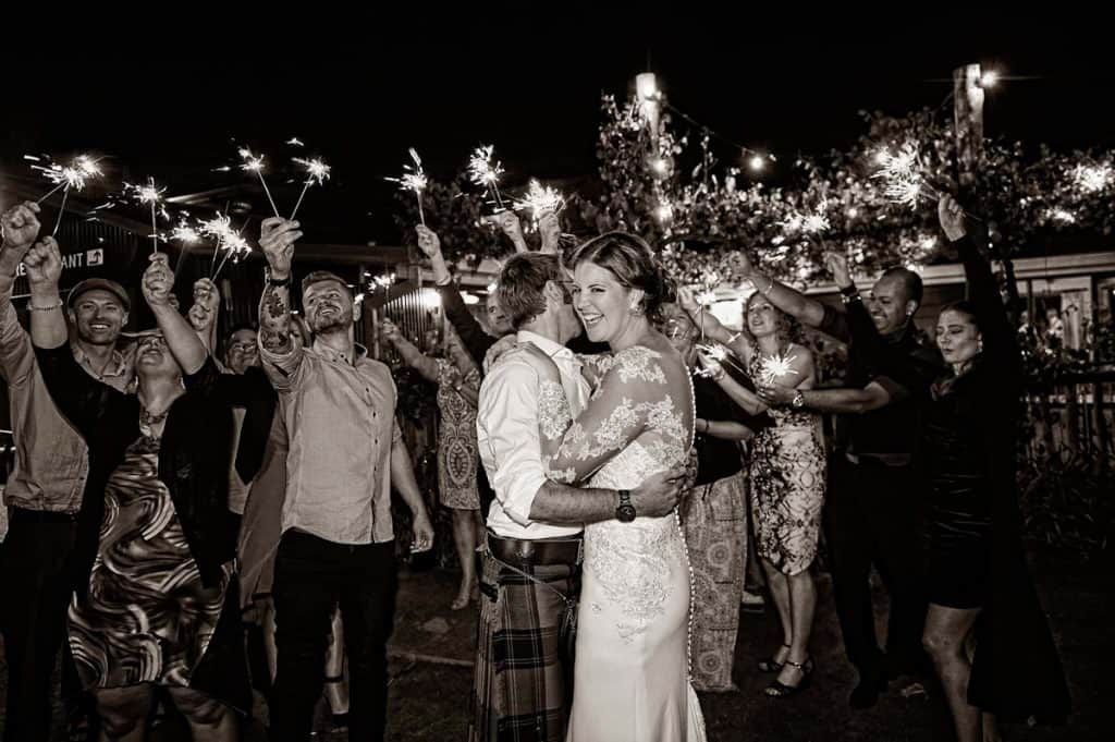 newly married couple dance in front of guests holding sparklers