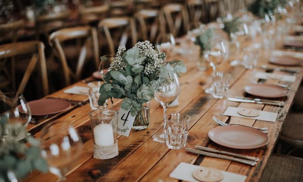 wedding reception ready for guests with timber tables, brown plates and green eucalyptus leaves and babies breath in vases