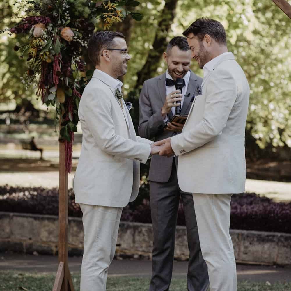 husband and husband hold hands as they exchange vows
