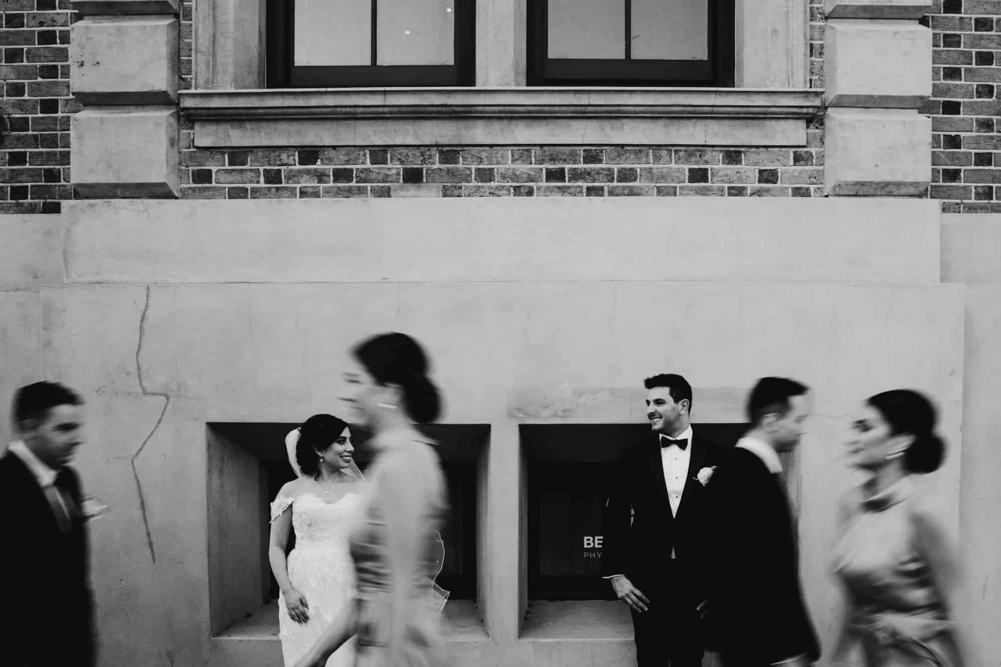 husband and wife sharing a moment as their bridal party walks by